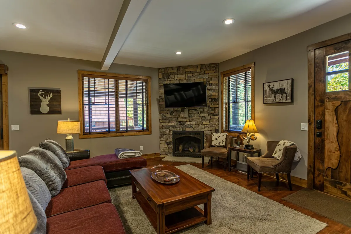 A spacious, welcoming interior featuring a stone fireplace, comfortable seating, and large windows. The setting is cozy and practical, suggesting a warm homecoming after outdoor activities, and suitable for pet owners and families.