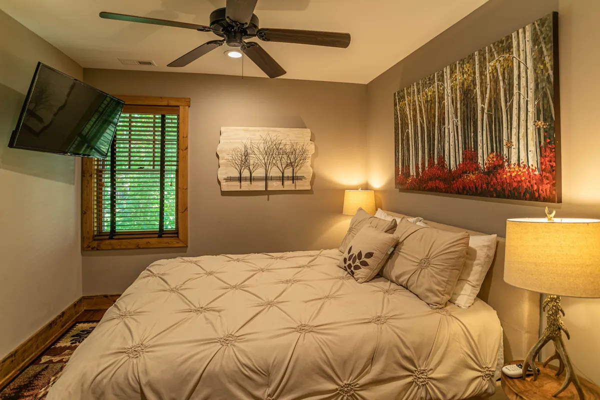 A serene bedroom featuring a comfortable queen bed with decorative pillows, nature-themed artwork, and a soft bedside lamp. The tranquil space is bathed in natural light, creating a welcoming atmosphere for restful nights or quiet reading.